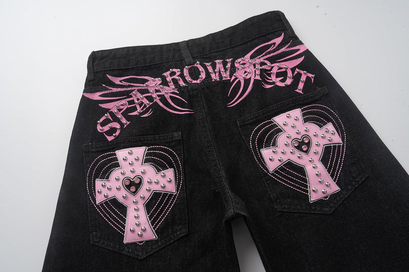 Back upper view of black wide-leg jeans showing pink graphic lettering and cross pockets