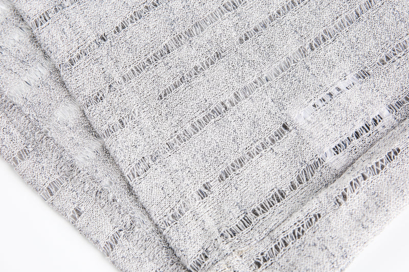 Close-up of gray open-knit sweater fabric with vertical distressing