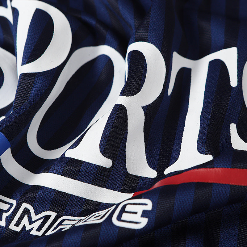Close-up of navy and black striped football-inspired jersey with bold white SPORT lettering and red accent trim