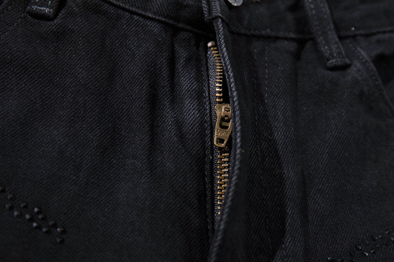 Close-up of the front zipper and button closure on black denim jeans