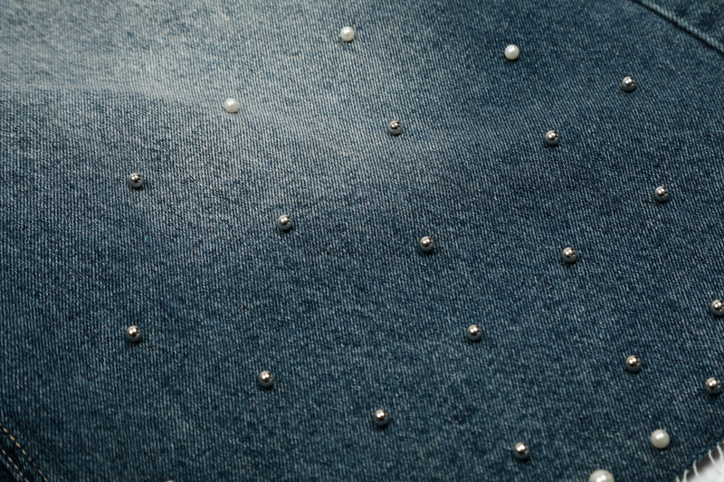 Close-up of denim shorts leg with scattered pearl stud accents