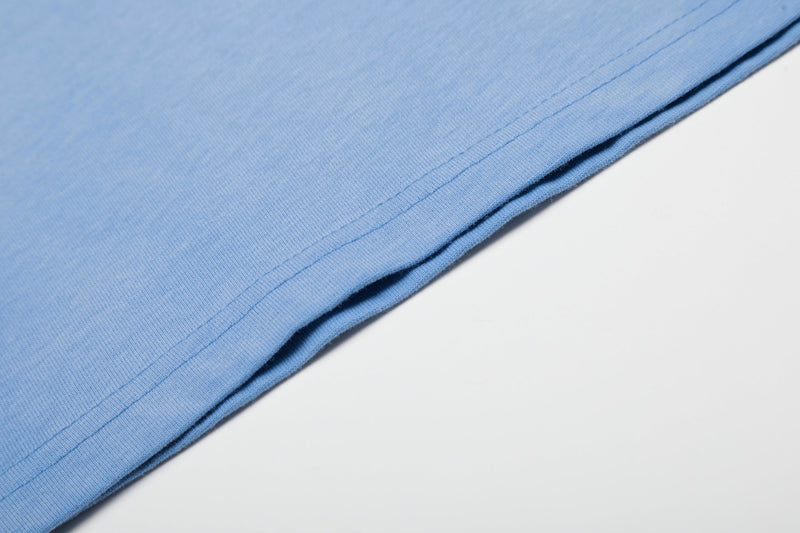 Light blue cotton T-shirt fabric close-up with neat stitched hem and smooth streetwear texture