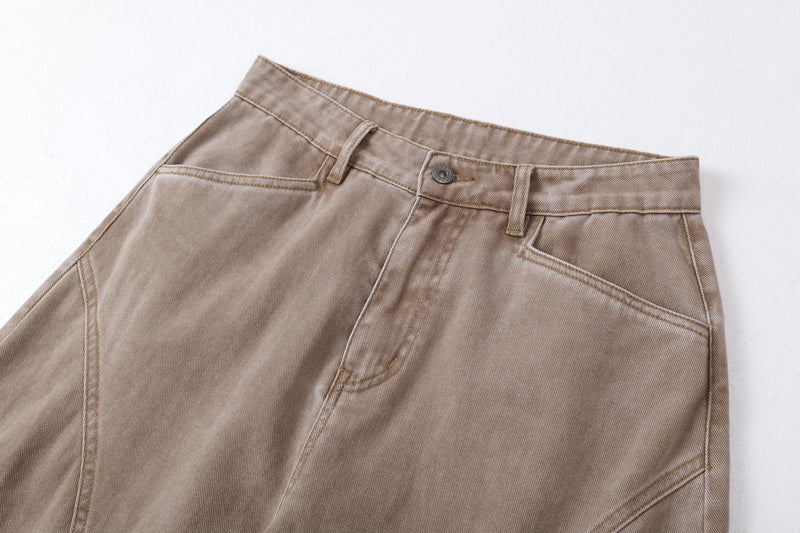 Close-up of brown jeans front waistband, button, and pocket seam