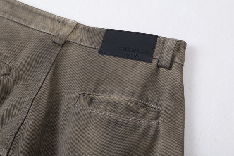 Close-up of back waistband, belt loop, and embossed black logo patch on olive jeans
