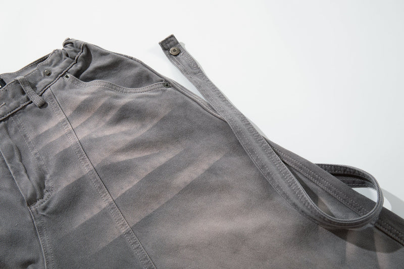 Close-up of gray jeans waistband with loose strap hanging down at the side