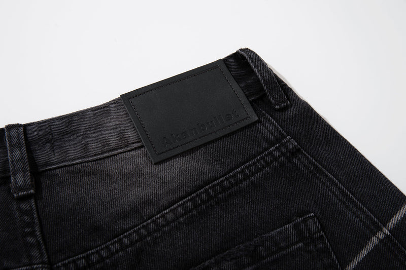 Close-up of the back waistband on washed black jeans with black logo patch and belt loops