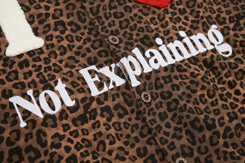 Leopard print button-up shirt with bold white Not Explaining graphic and large textured lettering across the chest