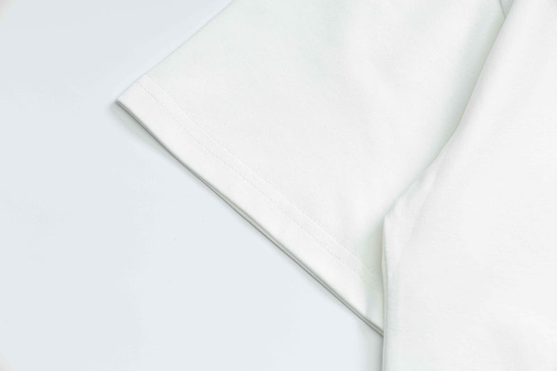 Close-up of a white vintage crest graphic t-shirt sleeve with clean stitched hem on a light background