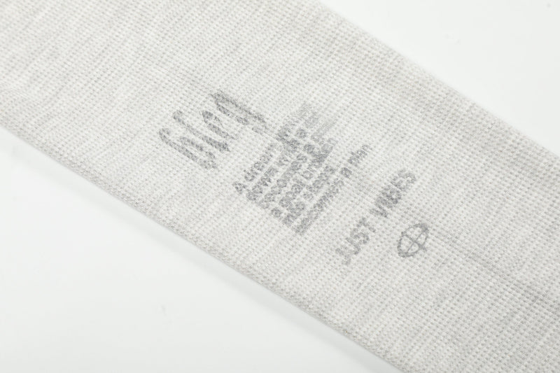 Close-up of sleeve graphic and text on light gray waffle knit long sleeve tee