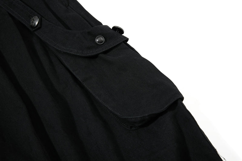 Close-up of black shorts cargo pocket flap with button detail on the side leg