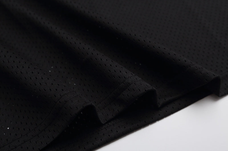 Close-up of black perforated mesh jersey fabric with textured folds on a clean white background