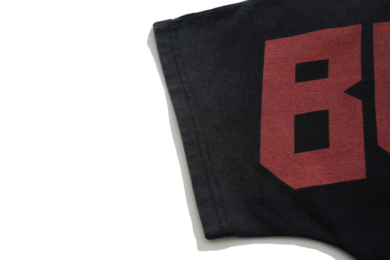 Close-up of a black oversized graphic tee with faded red print and vintage wash texture on the sleeve edge