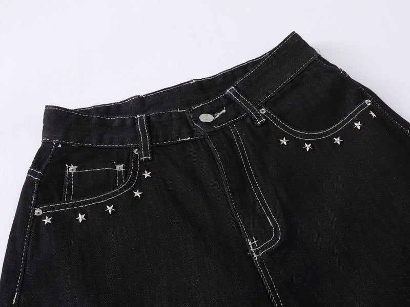 Close-up of black denim waist with star studs, belt loops, and front pocket stitching