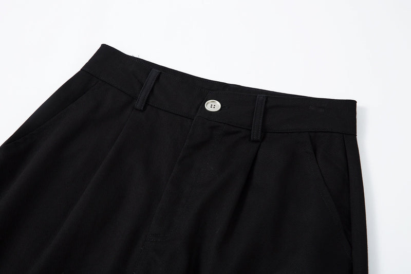 Close-up of black pants waistband, belt loops, and white button on textured twill fabric