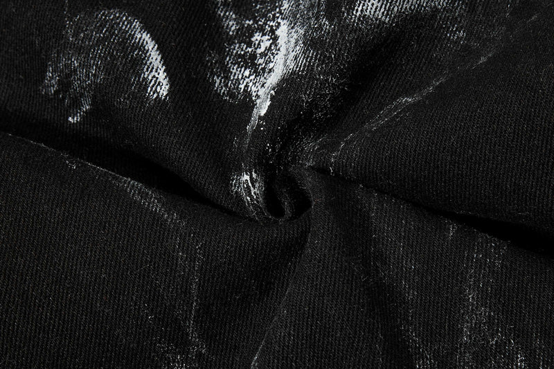 Close-up of black washed denim fabric with textured white distress marks