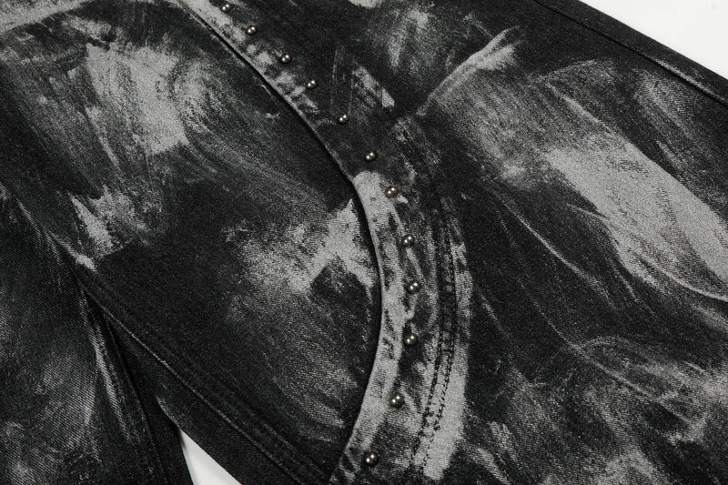 Close-up of studded curved seam across black painted jeans fabric