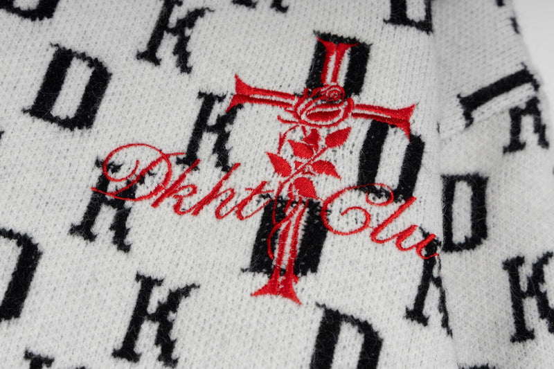Close-up of red Gothic cross embroidery over white knit monogram hoodie fabric
