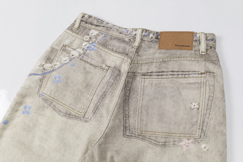 Close-up of back waistband and pockets on washed botanical print jeans with tan label patch