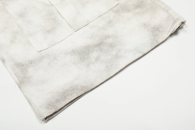 Close-up of the hem and side zipper detail on white washed cargo pants