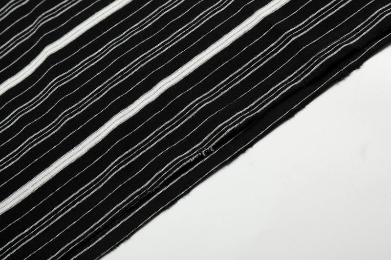 Close-up of striped tee fabric and distressed hem detail on black version
