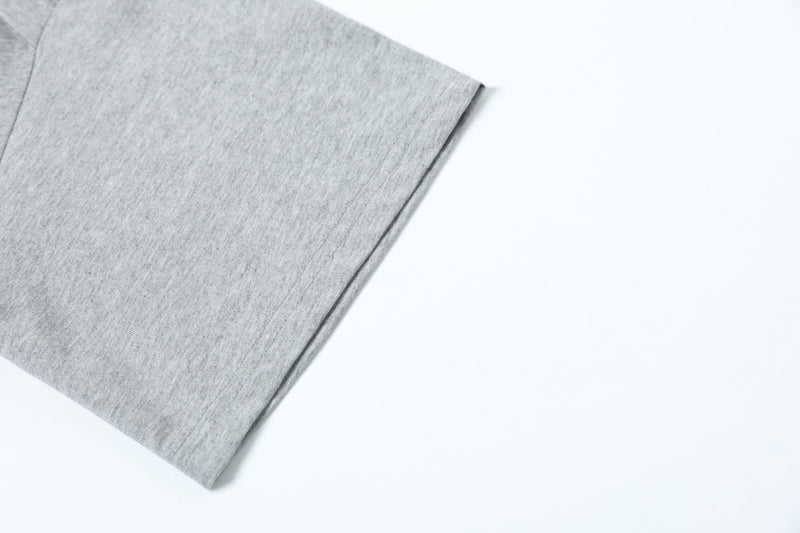 Close-up of a light gray structured short-sleeve T-shirt sleeve with folded panel detail on a white background