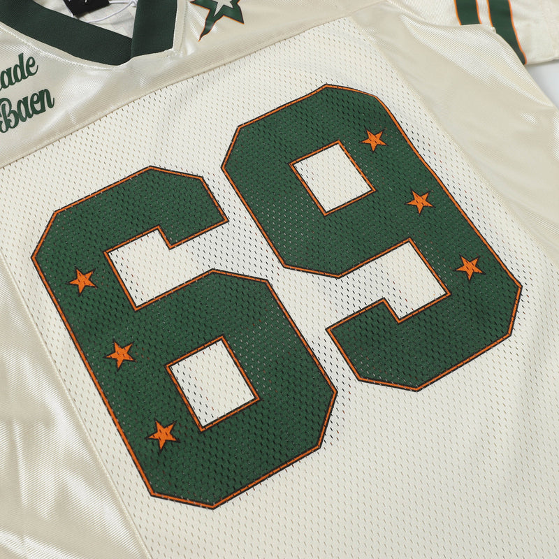 Retro football jersey tee with oversized green number 69, orange star accents, and cream varsity styling
