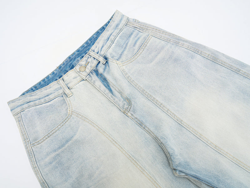 Close-up of light wash denim waist with button closure, belt loops, and front pocket seam