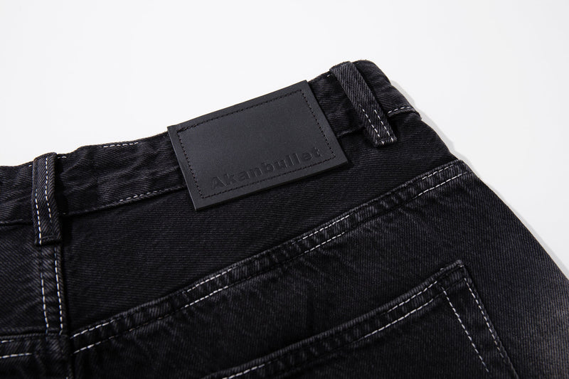 Close-up of the waistband logo patch on dark wash jeans with belt loop detail