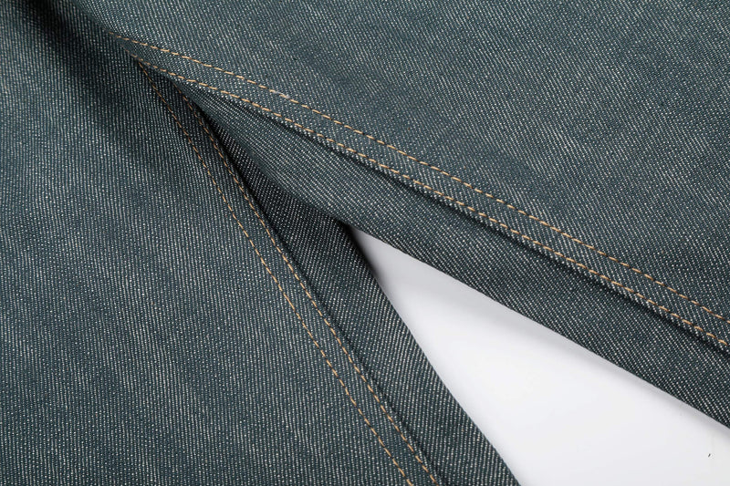 Close-up of a stitched leg seam on washed grey denim jeans