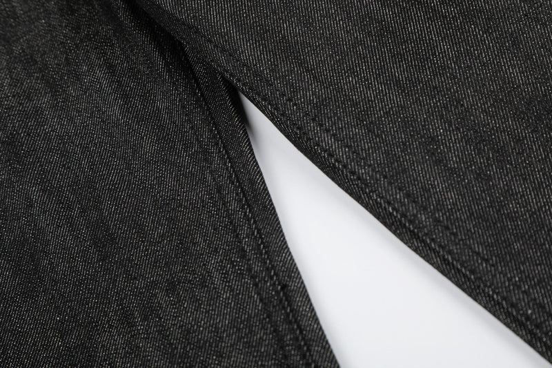 Close-up of black raw denim leg fabric and inner seam detail