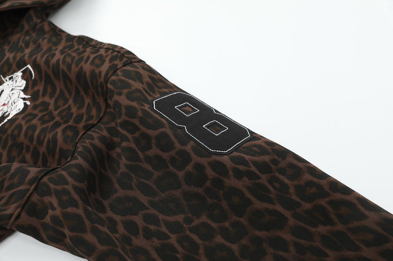Sleeve close-up of leopard print zip hoodie with black embroidered number 8 patch