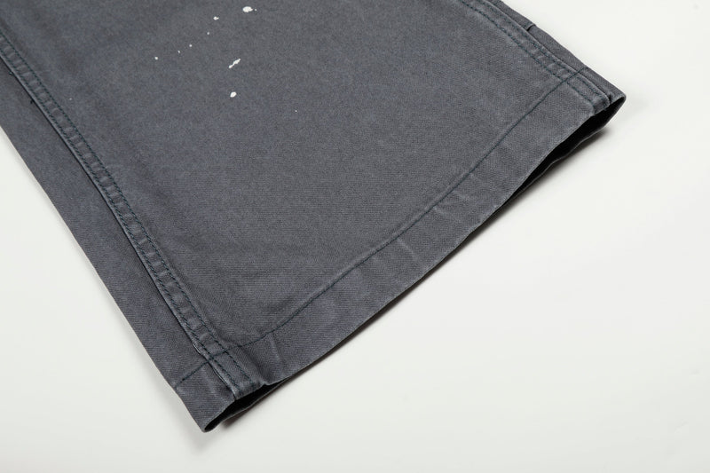 Close-up of gray jeans hem and wide leg opening with paint specks on the fabric