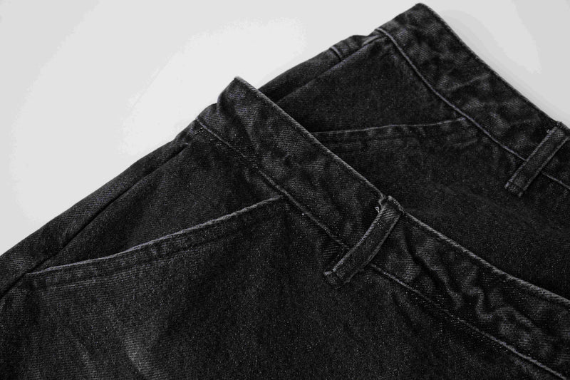Close-up of black denim shorts side seam and layered waistband