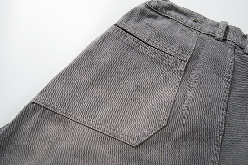 Close-up of gray jeans side cargo pocket flap and waistband seam