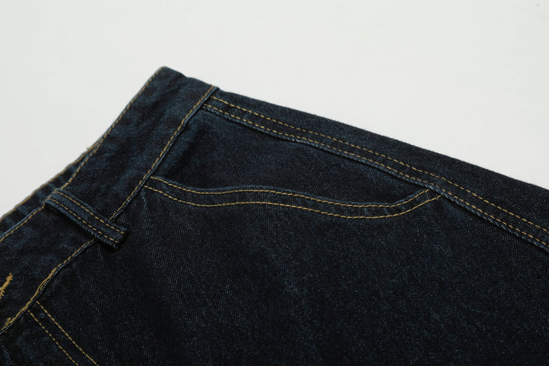 Close-up of back yoke seam on dark wash denim pants with contrast topstitching