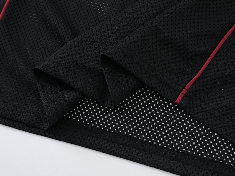 Close-up of black mesh shirt hem and sleeve cuff with perforated texture