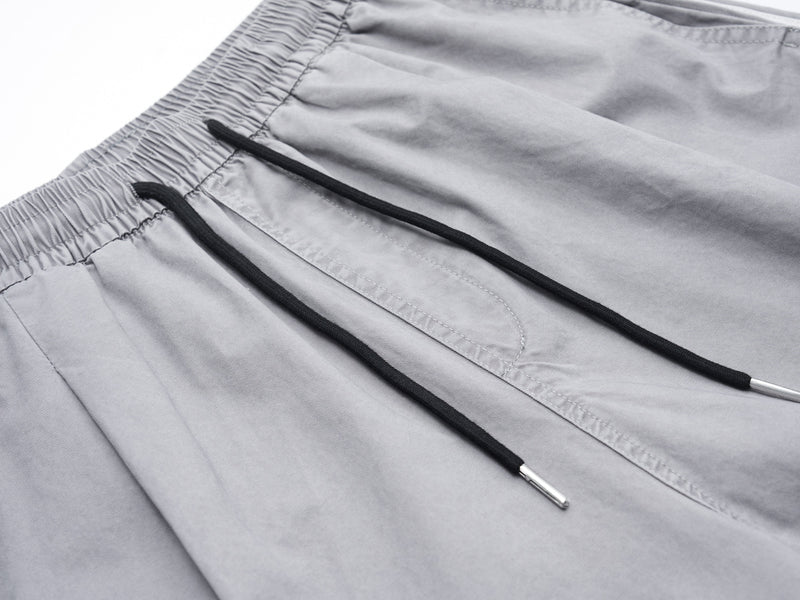 Close-up of gray shorts front drawstrings, seam detail, and elastic waistband