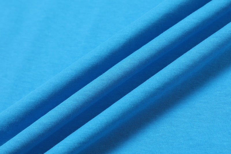 Close-up of bright blue jersey knit fabric with diagonal folds, showcasing a colorblock streetwear T-shirt texture