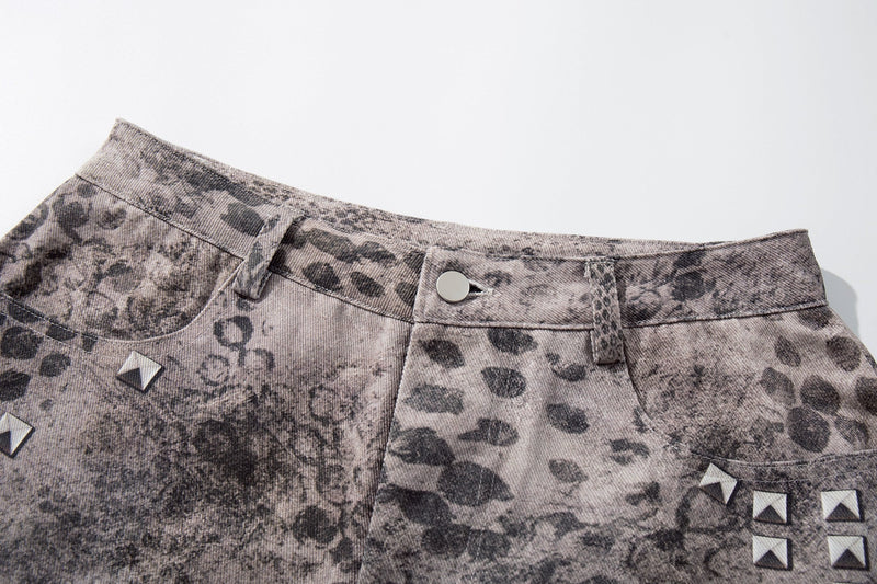 Close-up of front waistband on washed gray denim shorts with button closure and grunge print