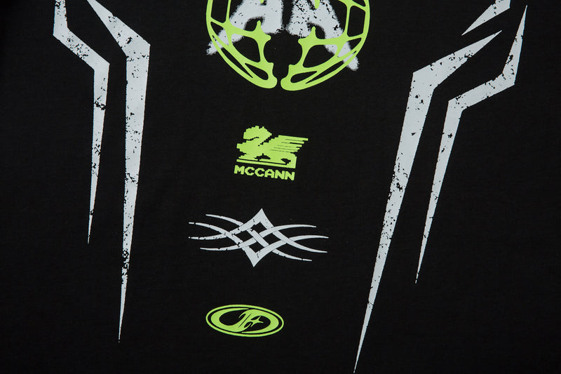 Close-up of black tee mid front with green Mccann logo and white geometric graphic