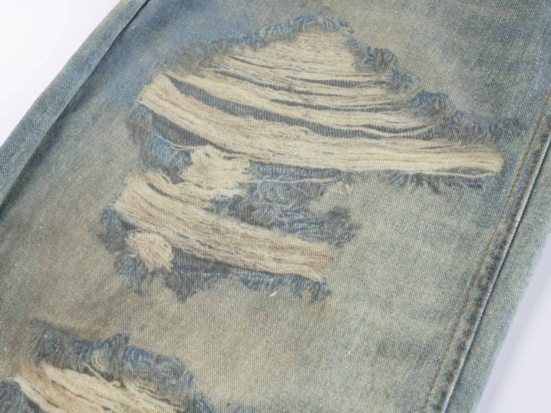 Close-up of ripped distressed patch on faded blue denim jeans