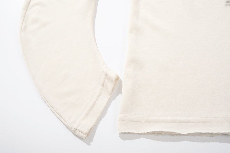 Close-up of sleeve and hem on cream long sleeve tee with stitched edges