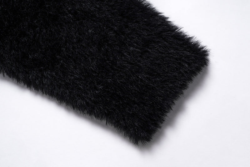 Close-up of a black fuzzy sweater sleeve cuff with plush texture