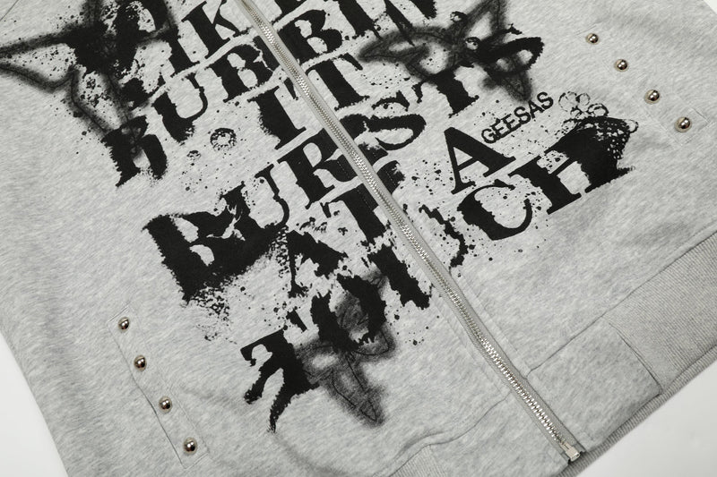 Close-up of light gray zip hoodie front with graffiti text, studs, and zipper
