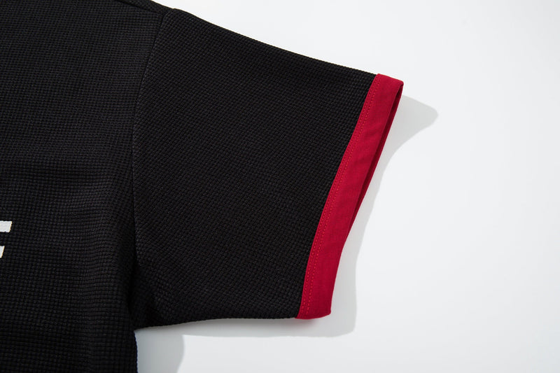 Black textured ringer T-shirt sleeve with bright red cuff on a clean white background