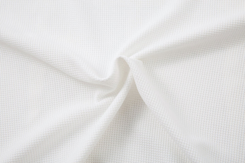 Close-up of white waffle-knit fabric with soft folds and texture