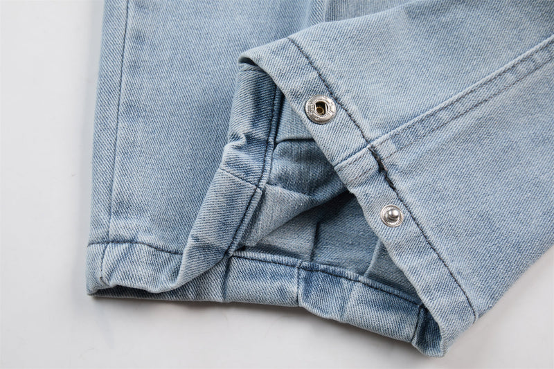 Close-up of light wash denim hem with side snap buttons and folded cuff detail