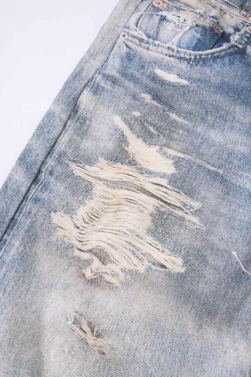 Close-up of ripped front leg detail on light wash distressed jeans