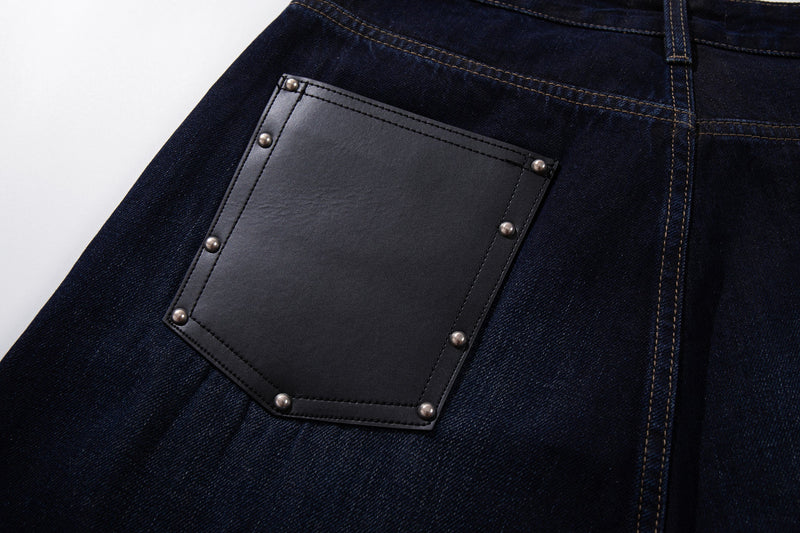 Close-up of one back leather patch pocket on deep indigo denim with metal rivets