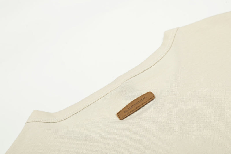 Cream tee upper back close-up with small leather neck patch